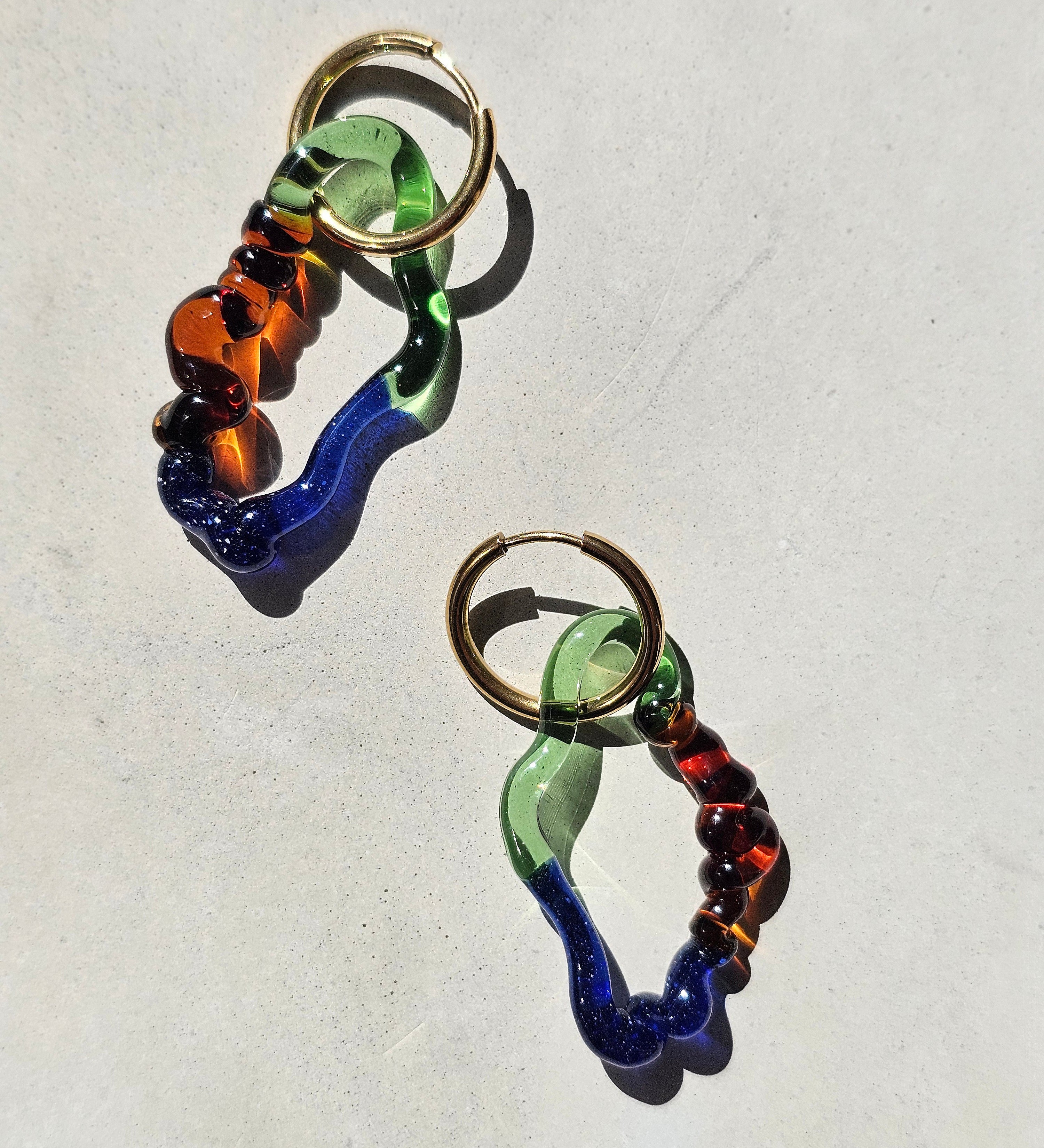 Drift Statement-Ohrringe aus blauem, grünem und amberfarbenem Glas im Sonnenlicht