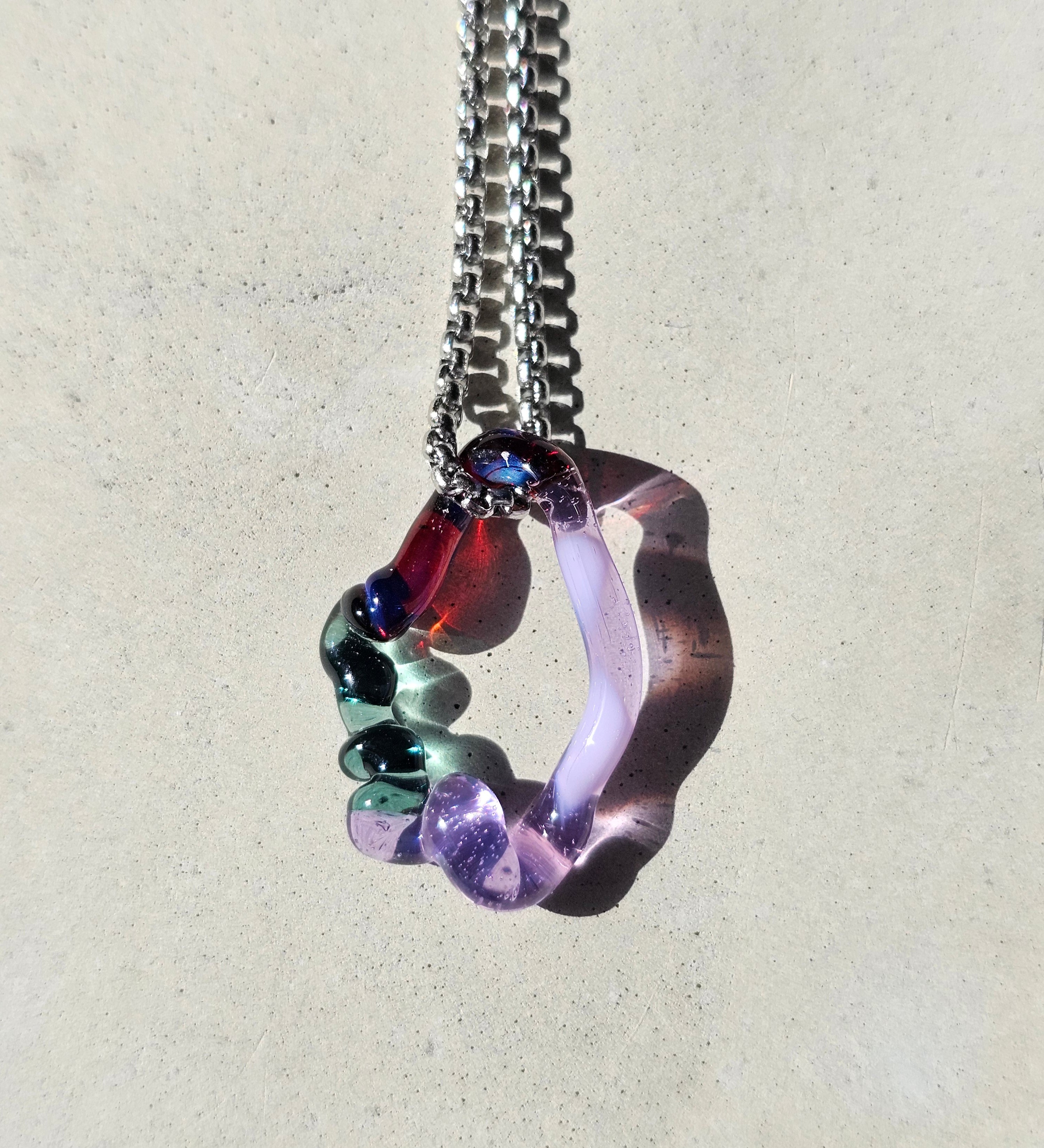 KLAPPERGLAS Echo Necklace candy mystic mit organischem Glasanhänger in Flieder und Petrol mit blau-roten Reflexen an silberfarbener Edelstahlkette